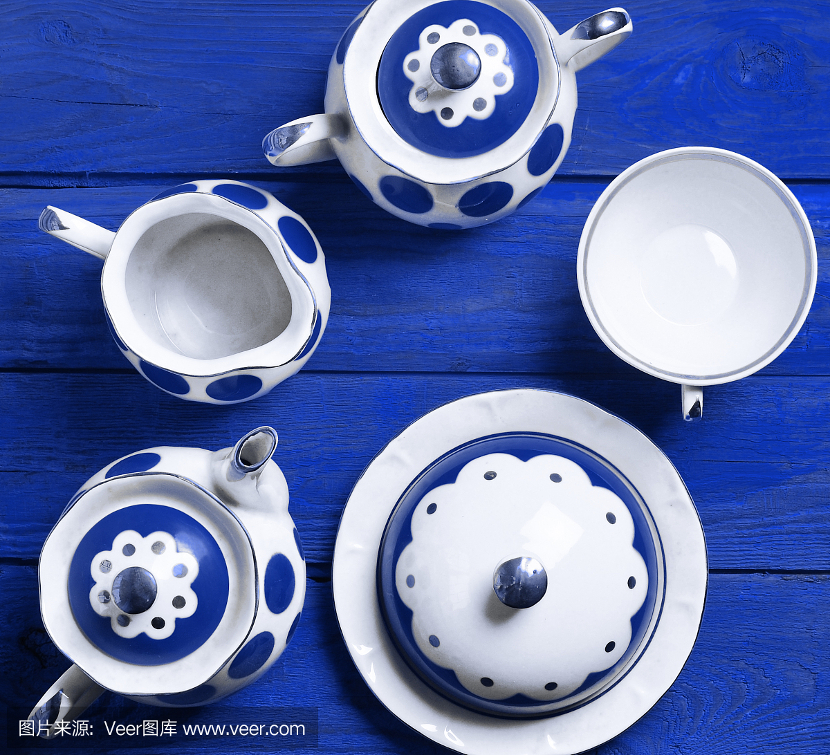 蓝色木桌上的陶瓷餐具。陶瓷茶壶,杯子,糖碗。